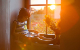young boy sitting next to nook window with sun shining in