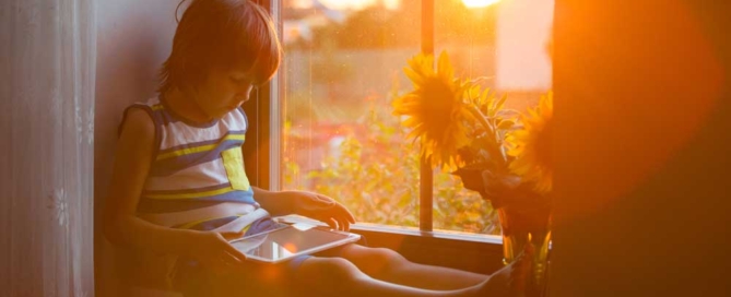 young boy sitting next to nook window with sun shining in