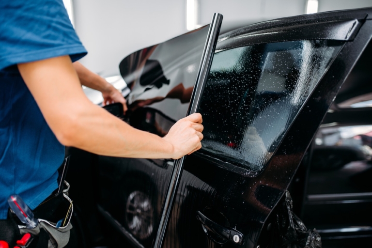 technician adding tint to car window