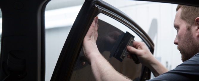 technician applies window tint to car