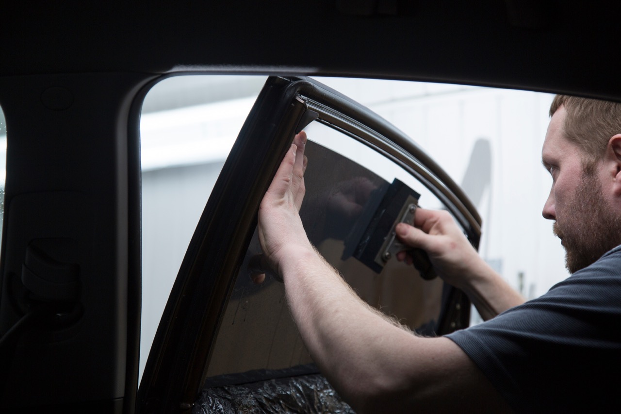 technician applies window tint to car