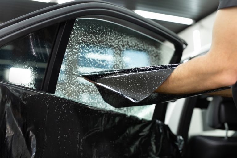 technician applying window tint to car passenger window